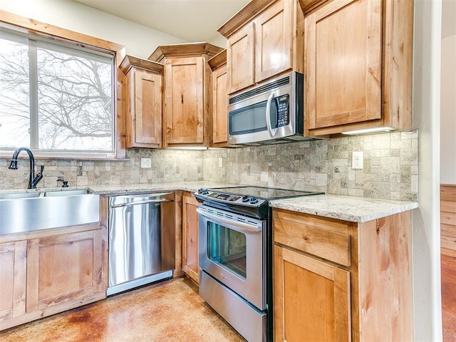 kitchen with decorative backsplash, appliances with stainless steel finishes, light stone countertops, light brown cabinetry, and a sink