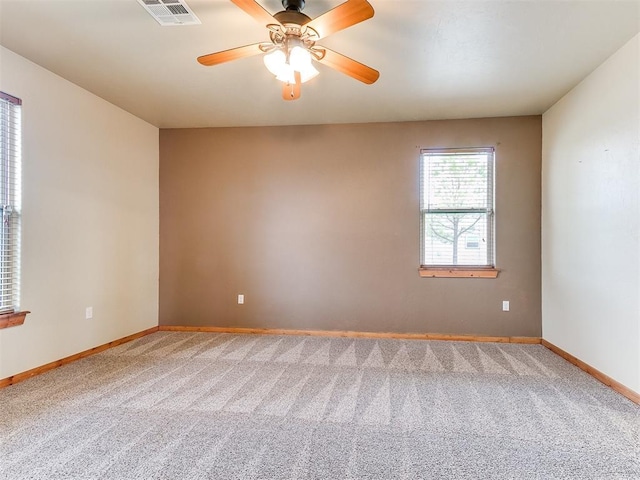 carpeted spare room with ceiling fan, visible vents, and baseboards