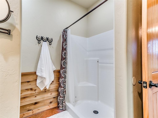 full bath featuring curtained shower and a textured wall