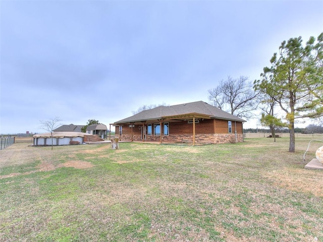 back of property featuring stone siding and a lawn