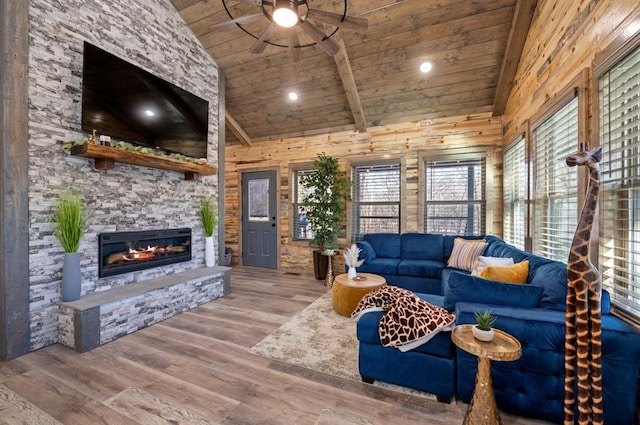 living room featuring wood ceiling, wooden walls, a stone fireplace, wood finished floors, and high vaulted ceiling