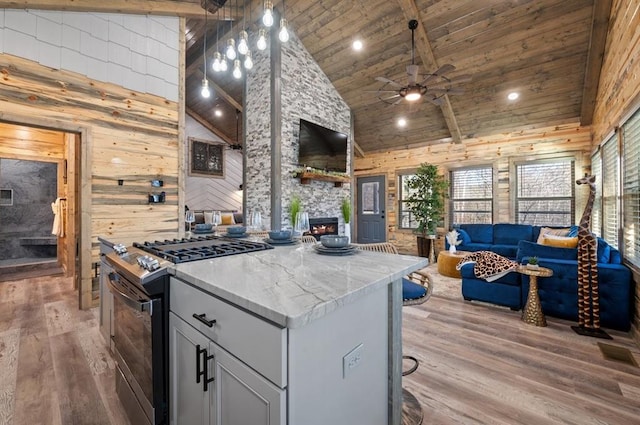 kitchen featuring wood walls, light wood-style flooring, open floor plan, and stainless steel range with gas stovetop