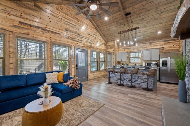 living room featuring light wood finished floors, wooden walls, wooden ceiling, beamed ceiling, and high vaulted ceiling