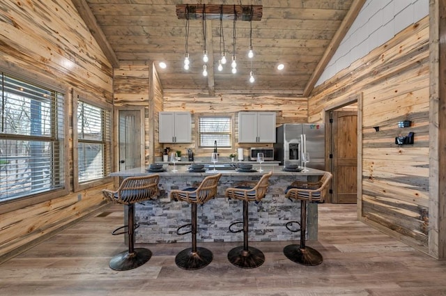 kitchen with stainless steel appliances, a breakfast bar, wooden ceiling, and white cabinets