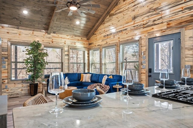 living room featuring lofted ceiling with beams, wooden ceiling, and a ceiling fan