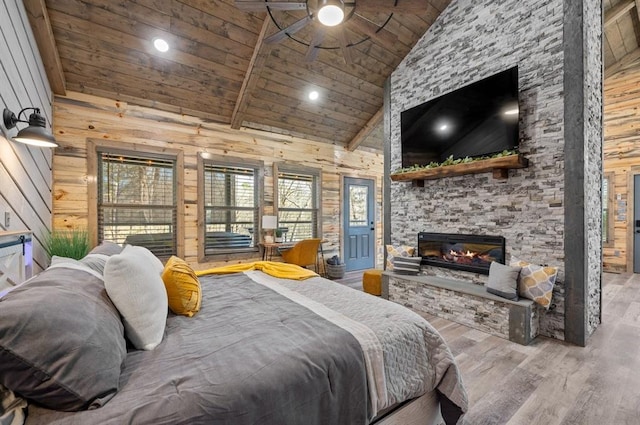 bedroom featuring wood ceiling, wood walls, a stone fireplace, wood finished floors, and high vaulted ceiling