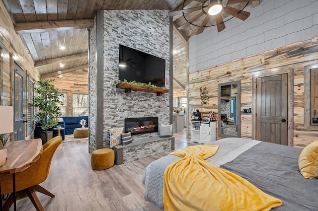 bedroom featuring wood ceiling, wood finished floors, a fireplace, high vaulted ceiling, and beam ceiling