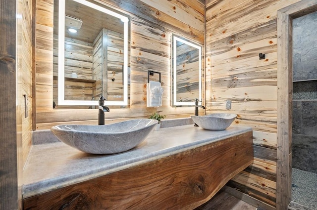 full bath featuring double vanity, wood walls, and a sink