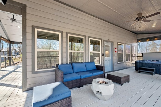 wooden deck featuring a ceiling fan, an outdoor living space with a fire pit, and a hot tub