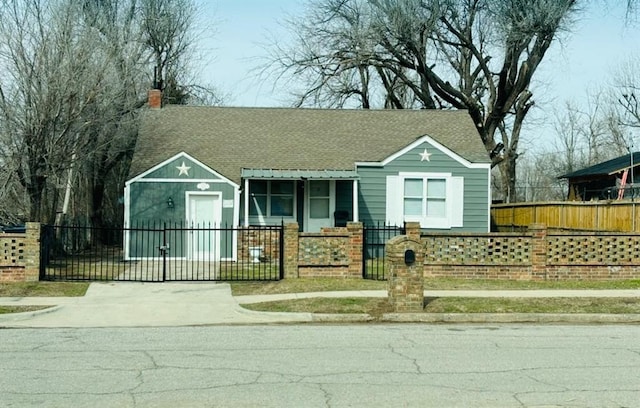 view of front facade with a fenced front yard, a shingled roof, and a chimney