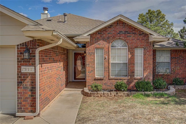 property entrance featuring a garage, brick siding, a shingled roof, and a chimney