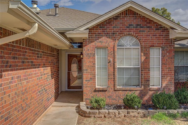 property entrance with brick siding and roof with shingles