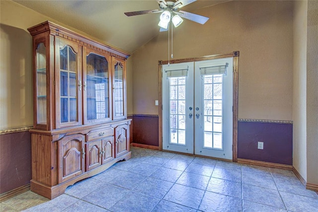 entryway with french doors, light tile patterned floors, a ceiling fan, wainscoting, and vaulted ceiling