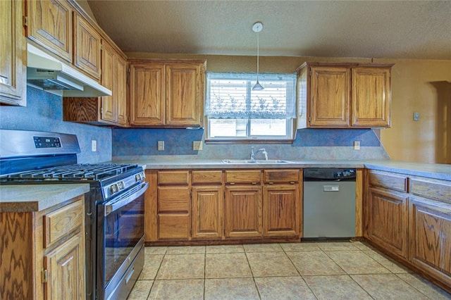 kitchen featuring light tile patterned floors, under cabinet range hood, stainless steel appliances, a sink, and brown cabinets