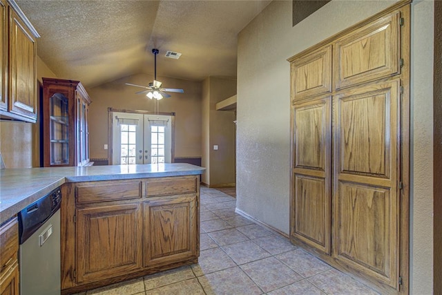 kitchen with a textured ceiling, light tile patterned floors, vaulted ceiling, french doors, and stainless steel dishwasher