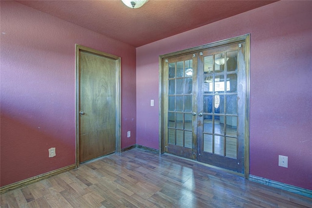 empty room featuring a textured ceiling, french doors, and wood finished floors