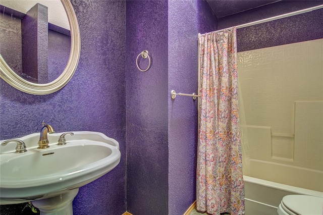 bathroom featuring a sink, toilet, and shower / bathtub combination with curtain