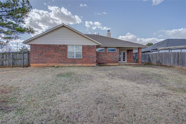 back of property featuring french doors, brick siding, a chimney, and a fenced backyard