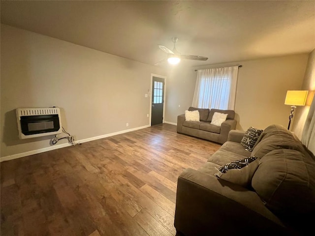 living area with baseboards, dark wood-type flooring, and heating unit