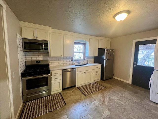 kitchen with a sink, white cabinets, light countertops, appliances with stainless steel finishes, and tasteful backsplash