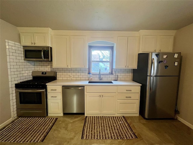 kitchen featuring stainless steel appliances, tasteful backsplash, light countertops, white cabinetry, and a sink