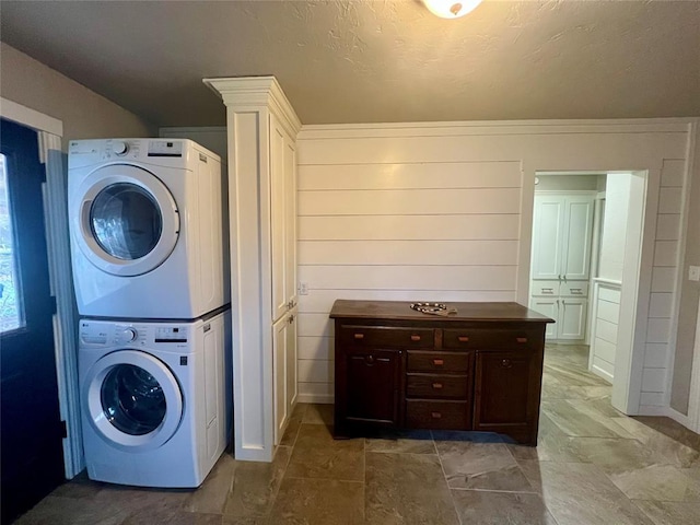 washroom with stacked washer and dryer, laundry area, and a textured ceiling