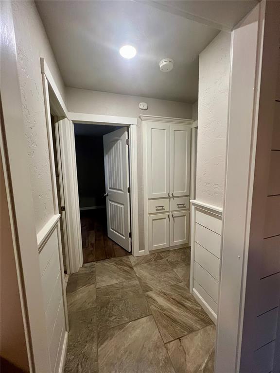 corridor with wainscoting and a textured wall