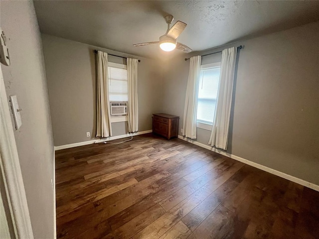 interior space featuring ceiling fan, cooling unit, dark wood finished floors, and baseboards