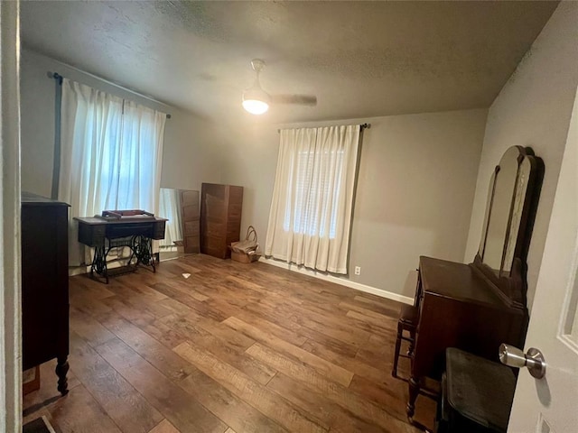 interior space with a healthy amount of sunlight, a textured ceiling, baseboards, and hardwood / wood-style flooring