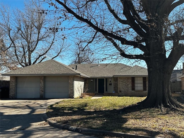 ranch-style home with a garage, driveway, brick siding, and roof with shingles