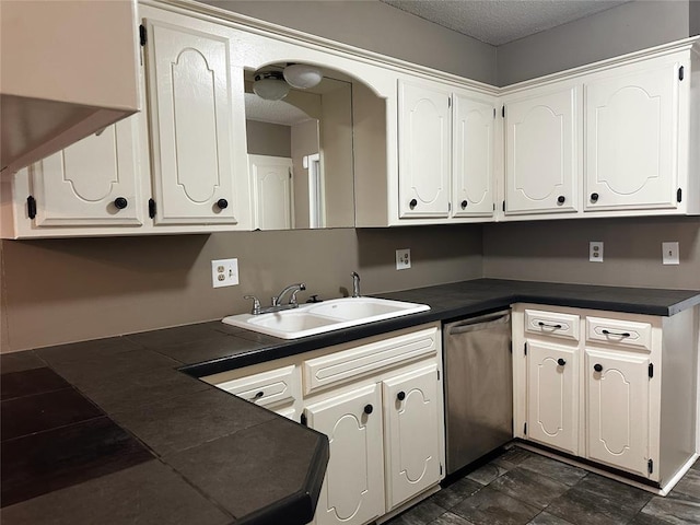 kitchen featuring dark countertops, white cabinets, a sink, and stainless steel dishwasher