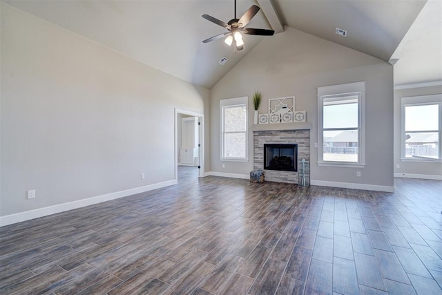 unfurnished living room featuring beamed ceiling, a stone fireplace, dark wood-style flooring, and a ceiling fan