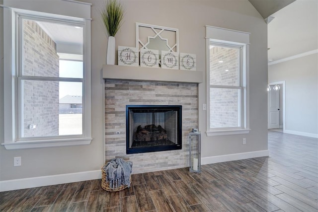 unfurnished living room with wood finish floors, a fireplace, a wealth of natural light, and baseboards