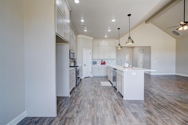 kitchen with wood finished floors, open floor plan, light countertops, appliances with stainless steel finishes, and backsplash