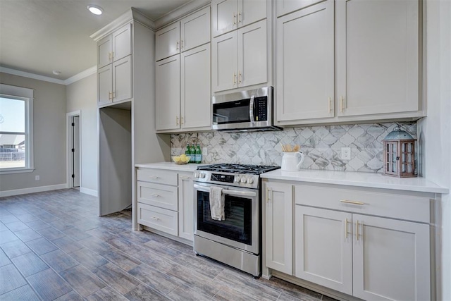 kitchen with tasteful backsplash, light countertops, appliances with stainless steel finishes, ornamental molding, and baseboards