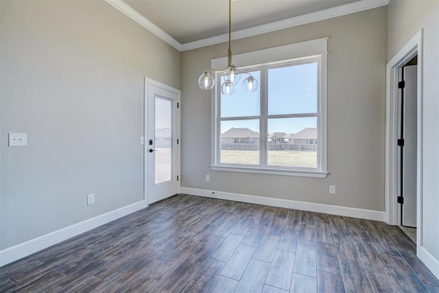 unfurnished dining area featuring dark wood-style flooring, crown molding, baseboards, and an inviting chandelier