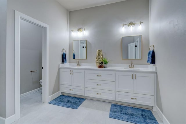 bathroom with a sink, toilet, and baseboards