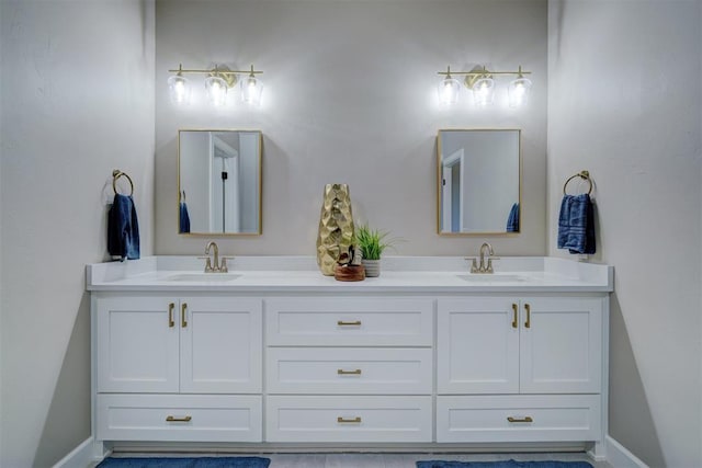 full bathroom featuring double vanity, baseboards, and a sink