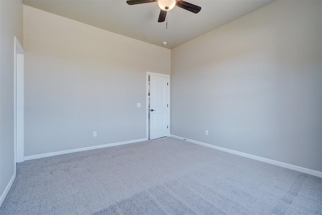 carpeted spare room featuring ceiling fan and baseboards