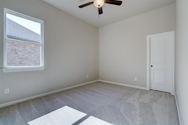 carpeted empty room featuring ceiling fan and baseboards