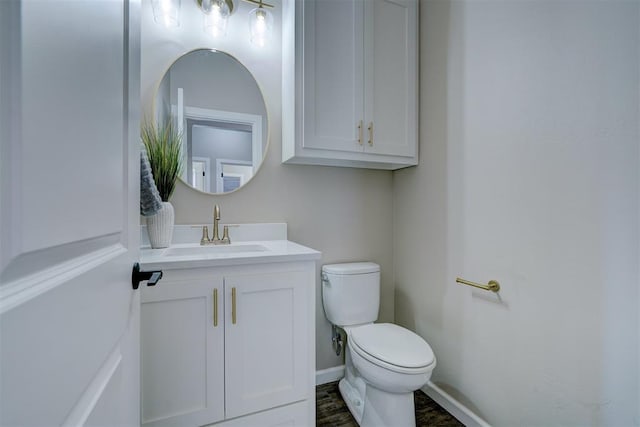 half bathroom with toilet, baseboards, and vanity