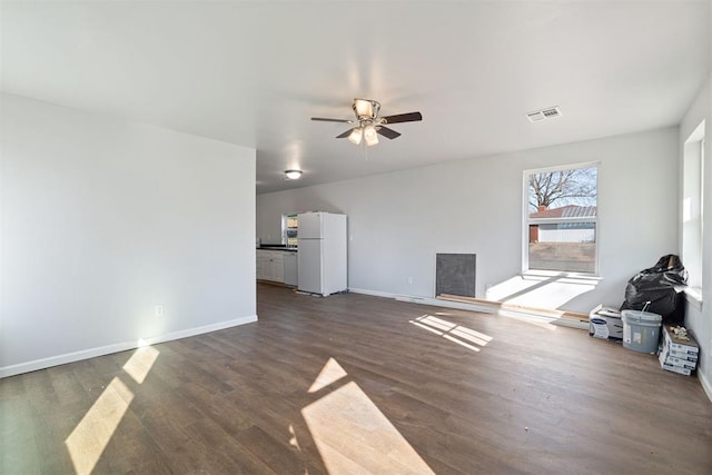 unfurnished living room with ceiling fan, visible vents, baseboards, and dark wood-type flooring