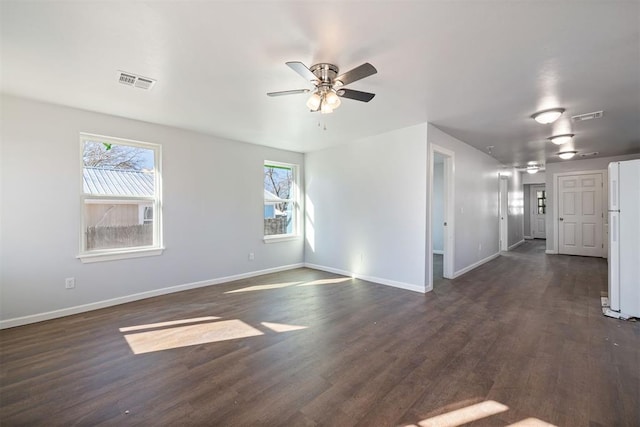 unfurnished room featuring a healthy amount of sunlight, dark wood-style floors, and visible vents