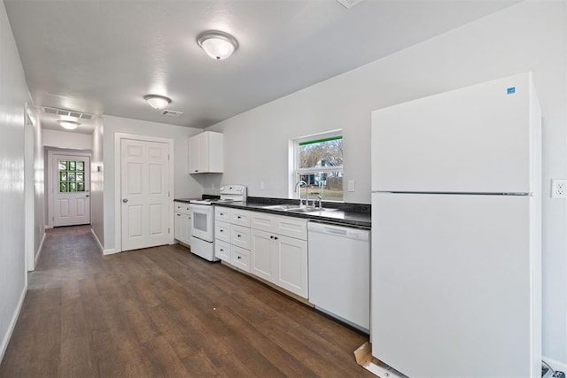 kitchen with white appliances, a sink, white cabinetry, dark wood-style floors, and dark countertops