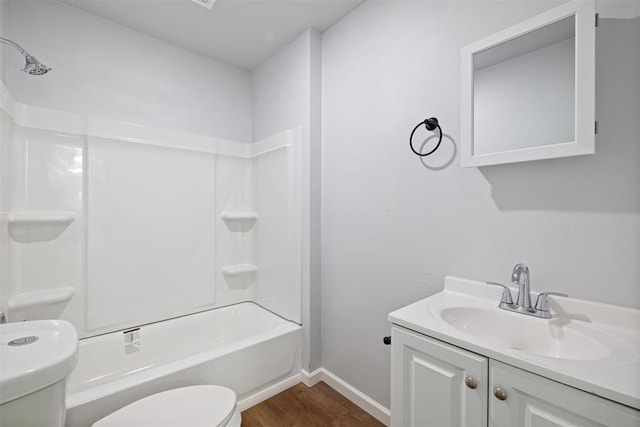 full bathroom with baseboards, toilet, wood finished floors, vanity, and washtub / shower combination