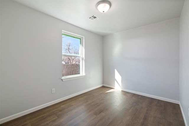 empty room featuring dark wood-style floors, baseboards, and visible vents