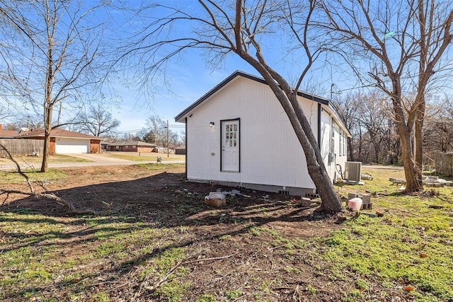 view of outdoor structure with a garage, an outdoor structure, dirt driveway, and central AC unit