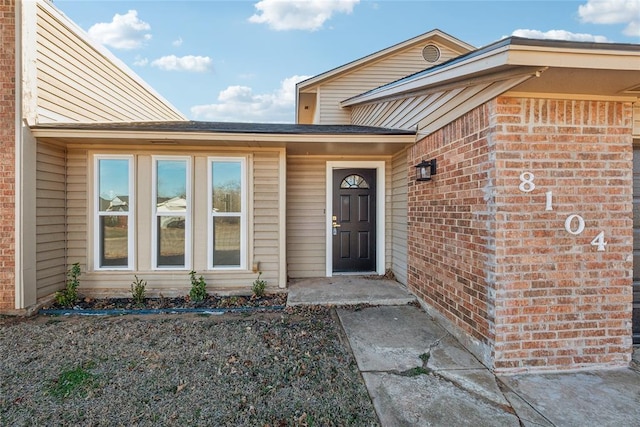 view of exterior entry featuring brick siding