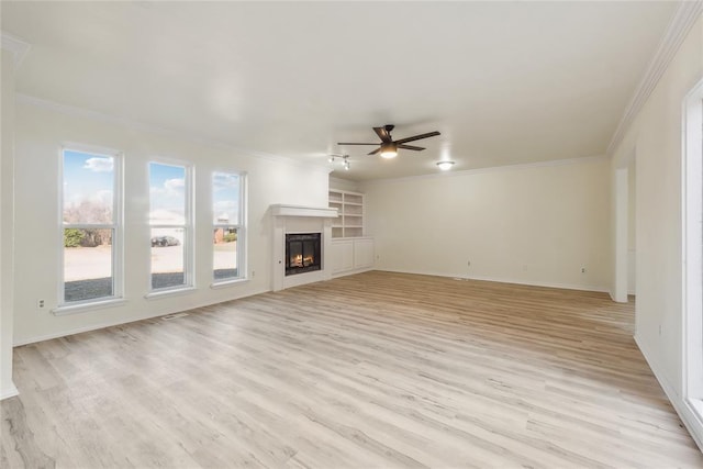 unfurnished living room featuring crown molding, a ceiling fan, light wood finished floors, and a lit fireplace