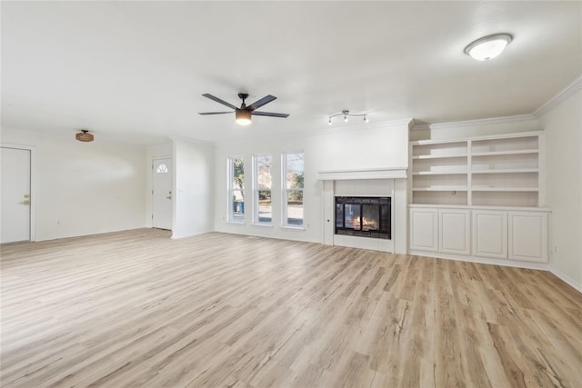 unfurnished living room with a glass covered fireplace, crown molding, light wood-style floors, and a ceiling fan